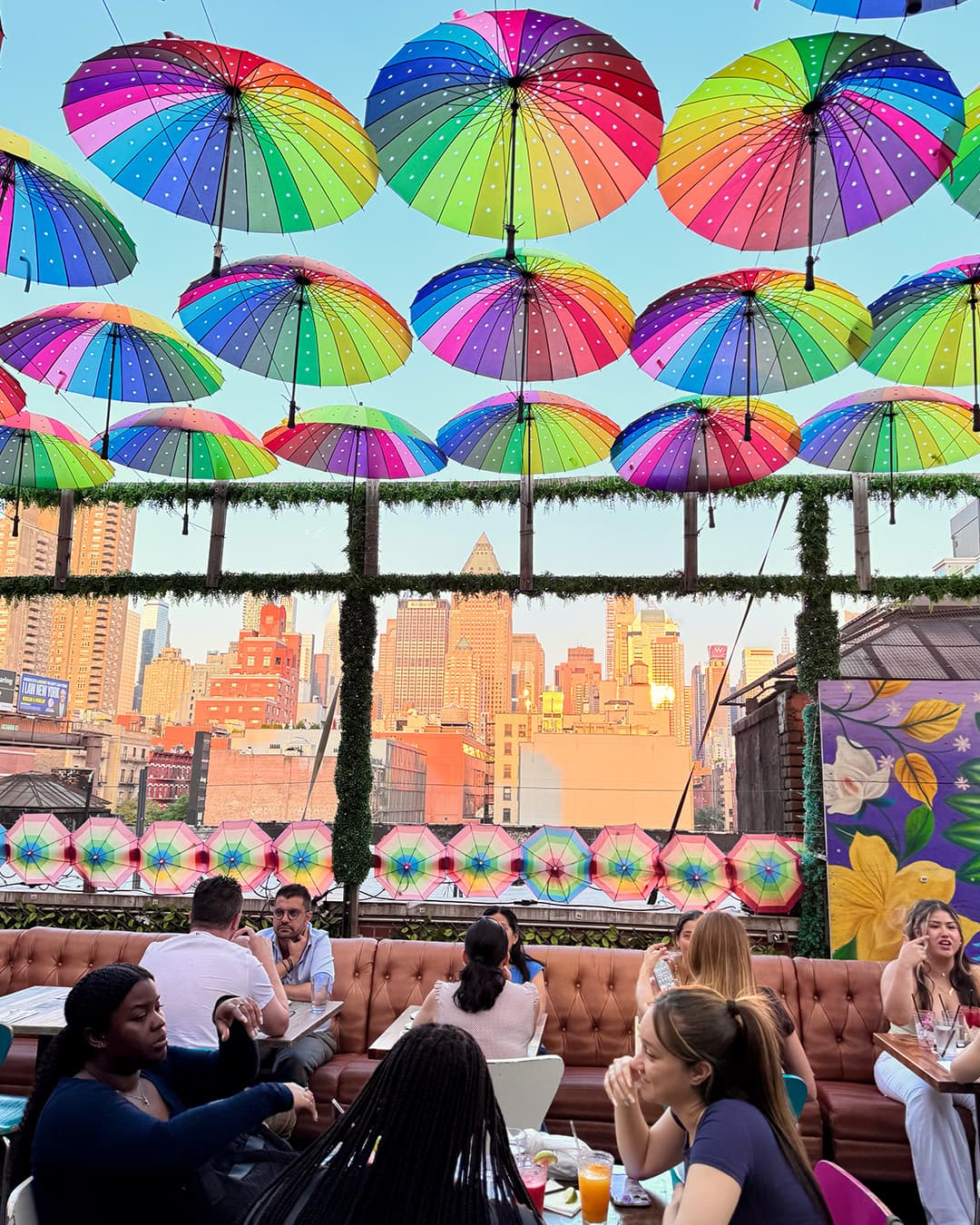 Golden hour Manhattan skyline seen from the Cantina Rooftop terrace under the rainbow umbrella canopy